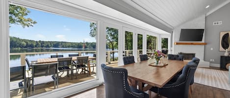 Un comedor amplio con una gran mesa de madera y sillas modernas, con vista a un lago.