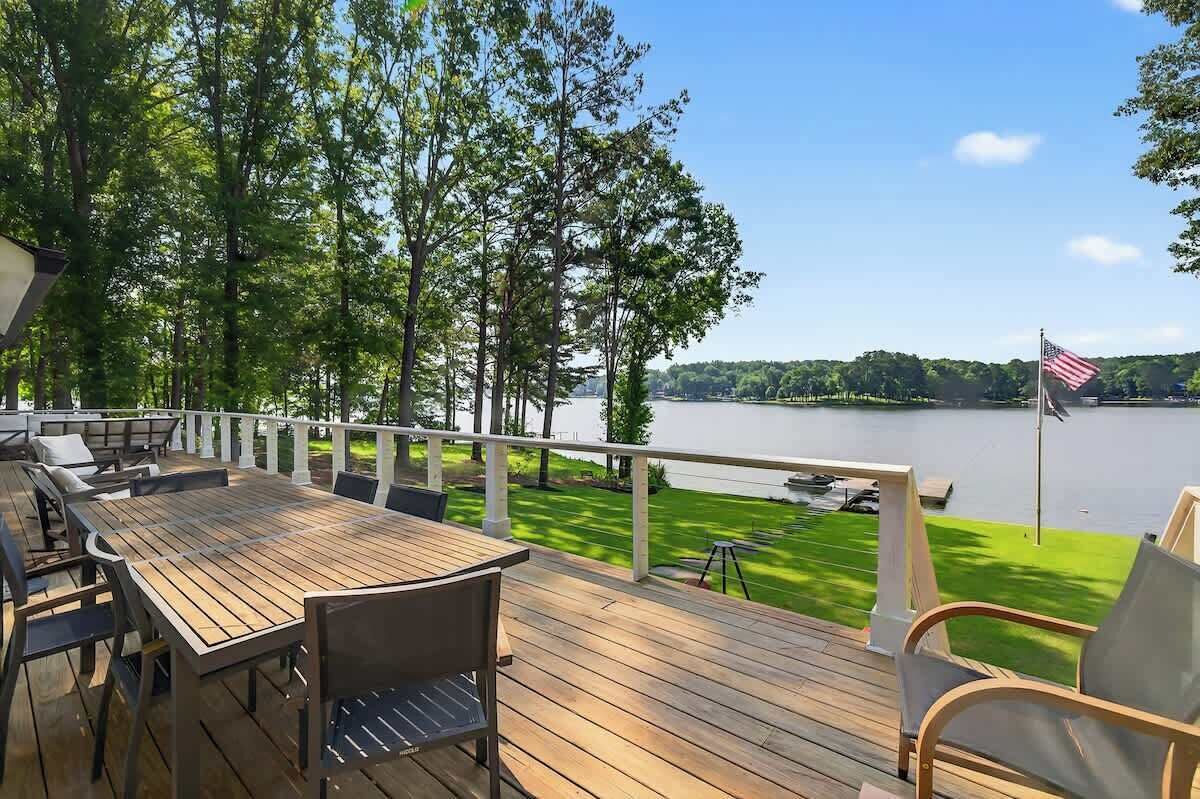 A wooden deck with outdoor furniture, a view of a lake, and an American flag.
