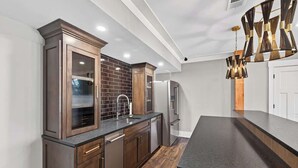 A modern kitchen with dark wood cabinets, a black countertop, and a unique chandelier. - Lakefront Retreat | Lake Oconee | Boat & Jet Skis (Eatonton)