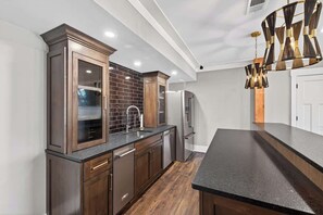 Una cocina moderna con armarios de madera oscura, una encimera negra y una lámpara colgante original.