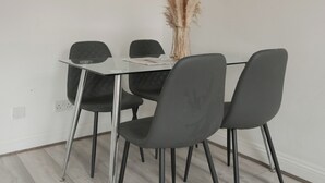A dining area with a glass table, four black chairs, and a vase of dried pampas grass. - Cozy apartment in the heart of Marylebone. 5 min walk to Baker Street Station! (London)