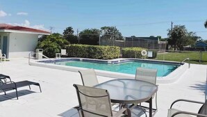 Une piscine avec une terrasse carrelée, des chaises longues et une table.