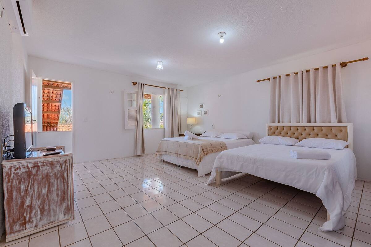 A hotel room with two beds, a desk, and a window with curtains.