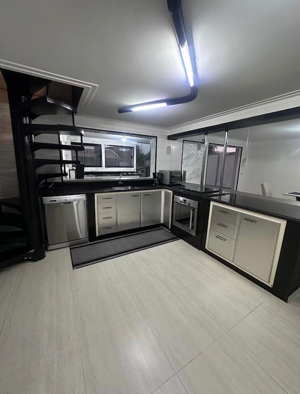A modern kitchen with a black and white color scheme, stainless steel appliances, and a large window providing natural light.
