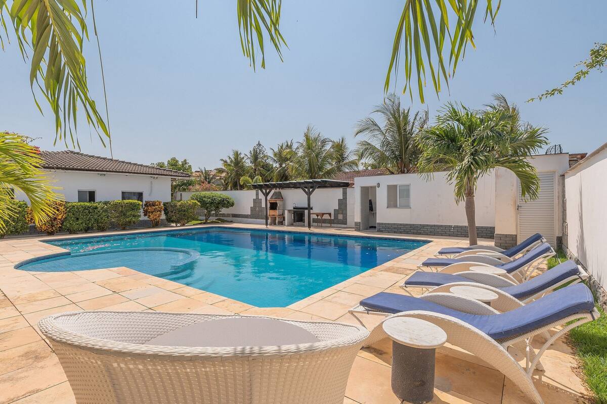 A swimming pool with lounge chairs and a covered seating area.