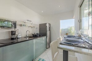 A modern kitchen with a glass island, stainless steel appliances, and a dining area with a table set for two.