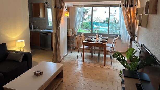 Ein modernes Wohnzimmer mit Essbereich, Küche und großen Fenstern mit Vorhängen.