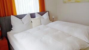 A neatly made bed with white linens, a grey headboard, and orange curtains. - Vacation home to feel good in, great pool to relax in, Donaucard included! (Engelhartszell)