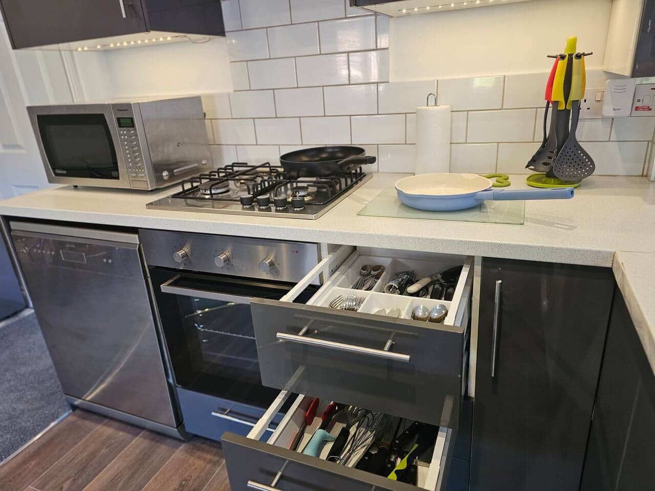 A modern kitchen with a microwave, gas stove, oven, and stainless steel dishwasher.