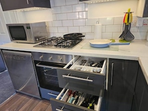 A modern kitchen with a microwave, gas stove, oven, and stainless steel dishwasher.