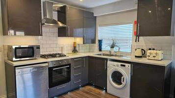 A modern kitchen with stainless steel appliances, a dishwasher, a washing machine, and a microwave.