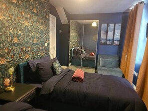 Un dormitorio con una cama grande, una mesita de noche, un espejo y vista a otra habitación.