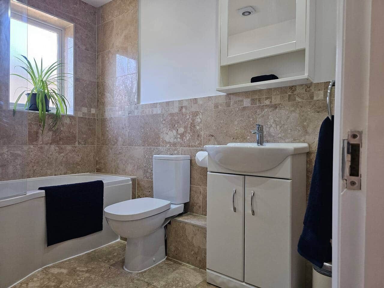 Ein Badezimmer mit Badewanne, Toilette, Waschbecken und einer Zimmerpflanze.