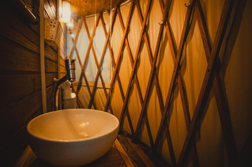 A bathroom with a wooden interior, a white sink, and a diamond-patterned wall.