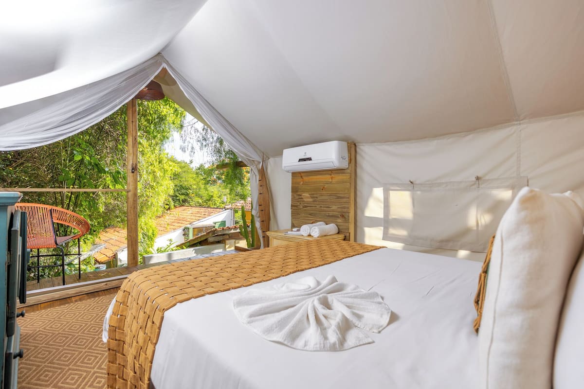 Ein Zelt-Schlafzimmer mit Bett, Fenster und Blick auf Grün.