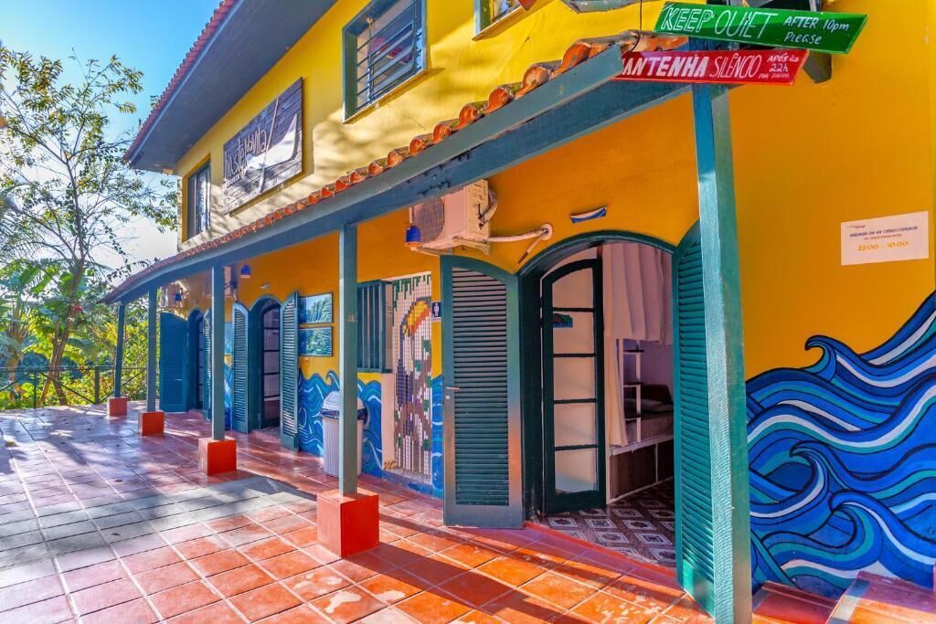 Un edificio colorido con una fachada vibrante, un porche cubierto y un mural.
