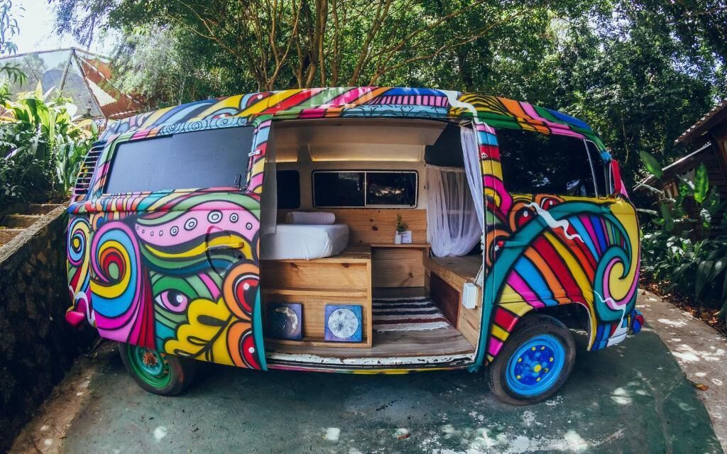 A colorful van with a small interior, including a bed and a seating area.