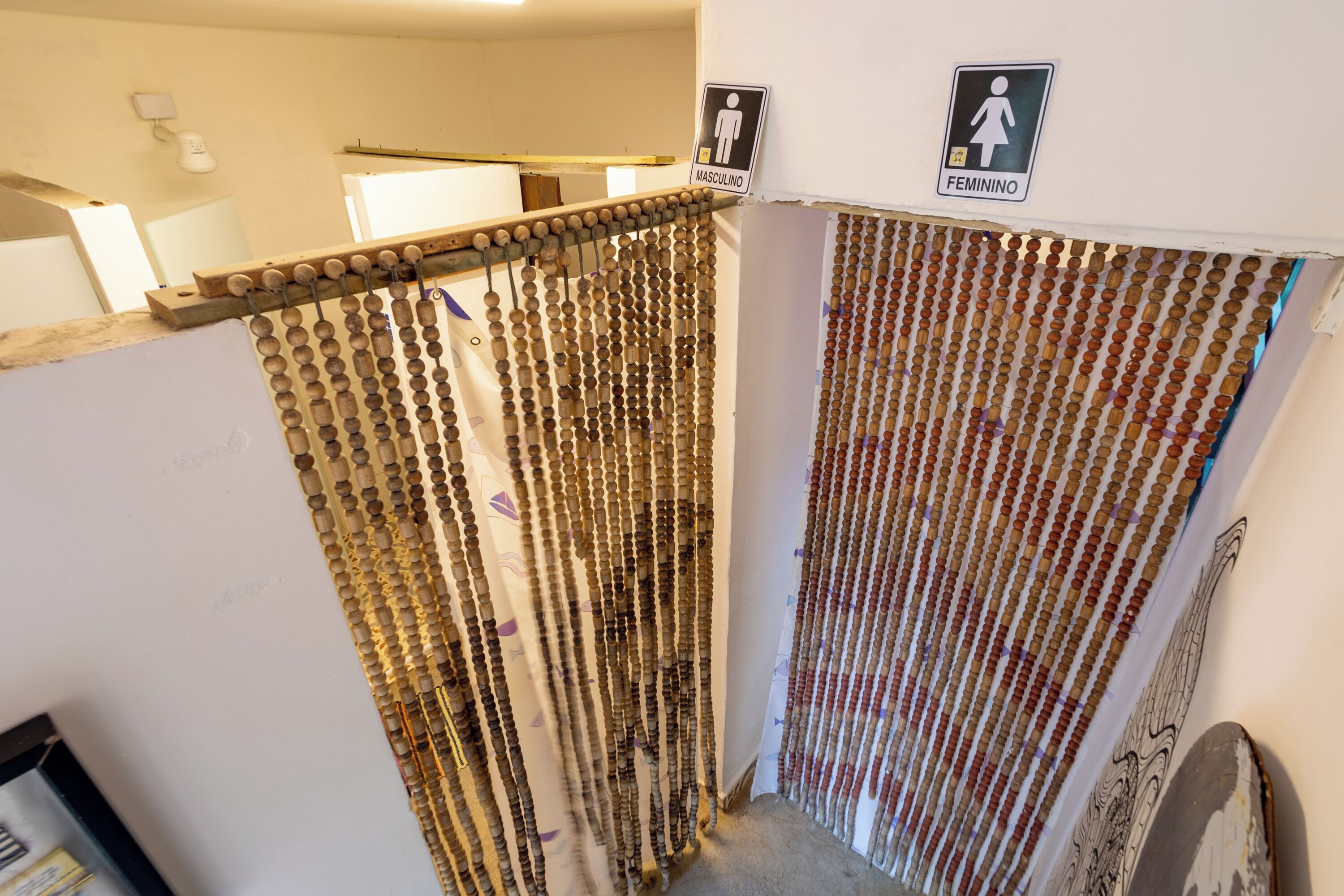 A corridor with a wooden slat partition and a sign indicating a men's and women's restroom.