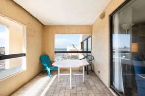 A balcony with a white table and two chairs, one blue and one black, overlooking a cityscape. - Cute Adjoining Bayside Studios #42 & #43 (South Padre Island)