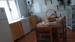 Une cuisine équipée d’une table à manger, de chaises, d’un réfrigérateur, d’une cuisinière, d’un évier et d’un four à micro-ondes.