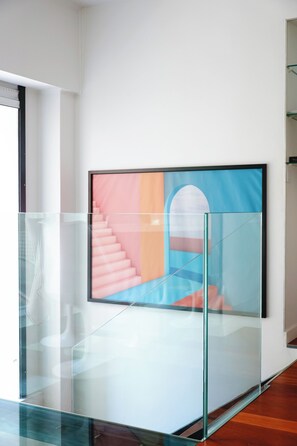 A modern interior with a staircase, a glass railing, and a colorful abstract painting on the wall. - Écrin d’architecte sous verrière • Marais (Paris)