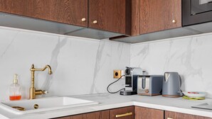 Una cocina con encimeras de mármol, un grifo dorado y una cafetera.