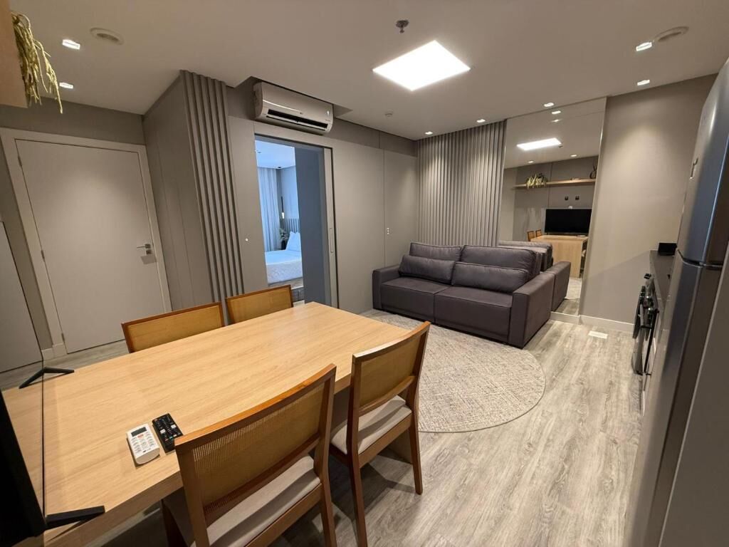 Un salon moderne comprenant un canapé, une table à manger avec des chaises et un coin cuisine avec un réfrigérateur.
