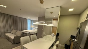 Una habitación de hotel moderna con comedor, sofá, cama y área de cocina.