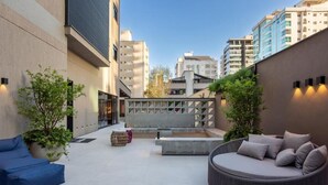 Un área de patio al aire libre con una zona de estar circular, un sofá azul y una pequeña mesa.