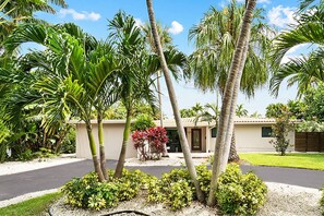 A residential area with palm trees, a house with a tiled roof, and a well-maintained lawn. - Luxury 4BR Retreat w/ Heated Pool, Jacuzzi® Hot Tub & Indoor/Outdoor Games (Hollywood)