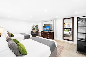 A modern hotel room with two beds, a TV, a wardrobe, and a large mirror. - Luxury 4BR Retreat w/ Heated Pool, Jacuzzi® Hot Tub & Indoor/Outdoor Games (Hollywood)