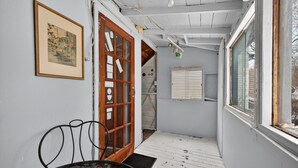A narrow hallway with a wooden door, a framed picture on the wall, and a window on the right. - Cozy & practical apartment in Hull 5 min to Ottawa (Gatineau)