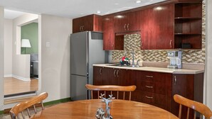 A compact kitchen with dark wood cabinets, a stainless steel refrigerator, and a coffee maker on the counter. - Cozy & practical apartment in Hull 5 min to Ottawa (Gatineau)
