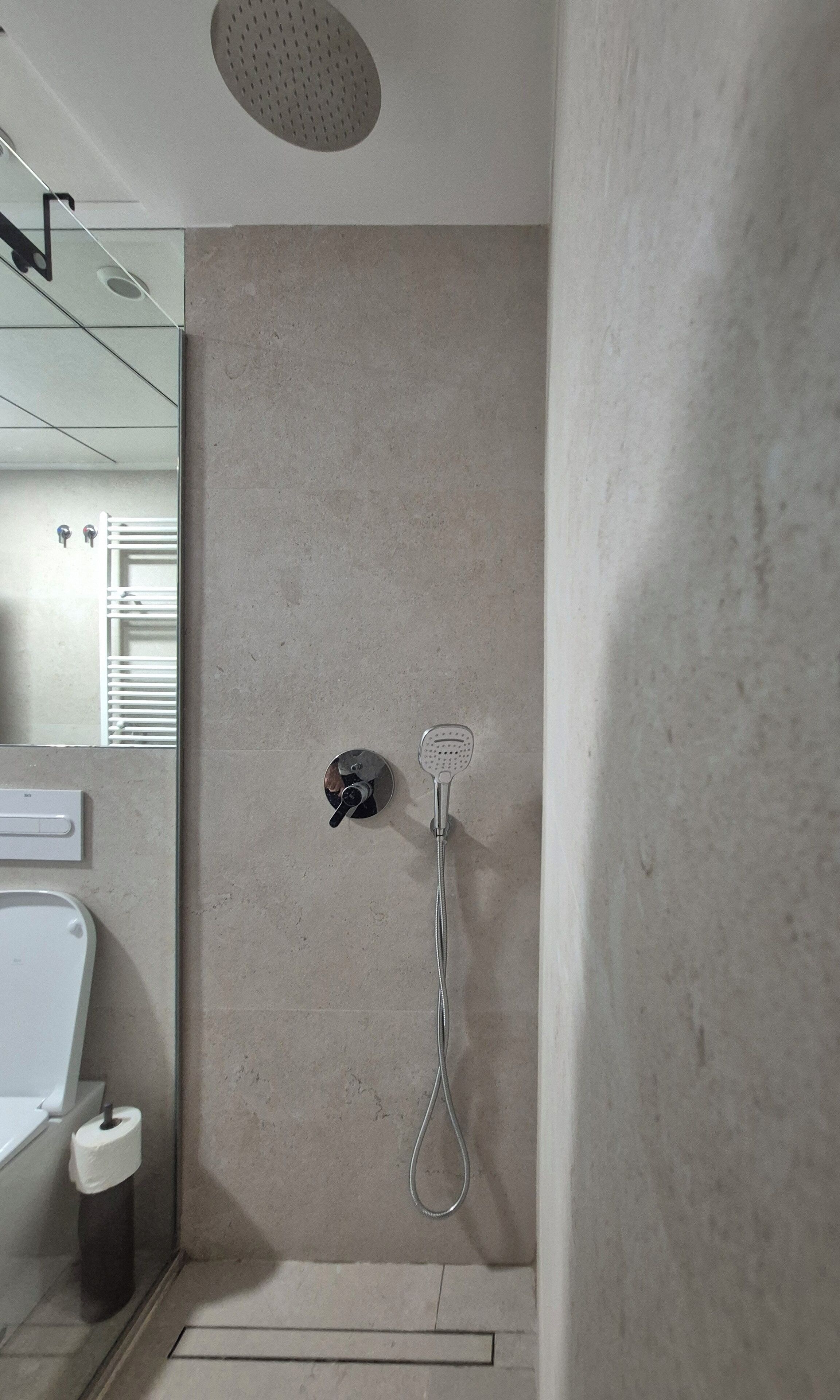 Baño con ducha, inodoro y espejo.