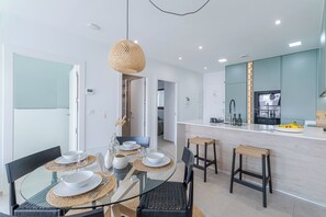 A modern kitchen with a central island, a dining area with glass tables, and a living space with a sofa. - Escape to LA Paz - sun, peace and luxury awaits you! 🌞 (Los Alcázares)