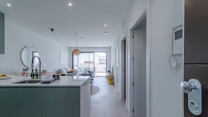 Una cocina moderna con una isla central, una zona de comedor con mesa y sillas, y vistas al exterior.