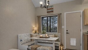 A cozy room with a bench, a table, and a window with curtains.