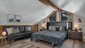A bedroom with a bed, a sofa, a nightstand, and a window.