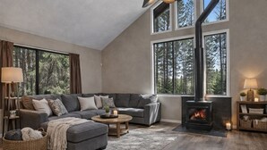 A cozy living room with a fireplace, large windows, and a comfortable sofa.