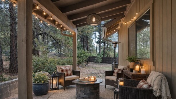 An outdoor patio with wicker furniture, string lights, and candles.
