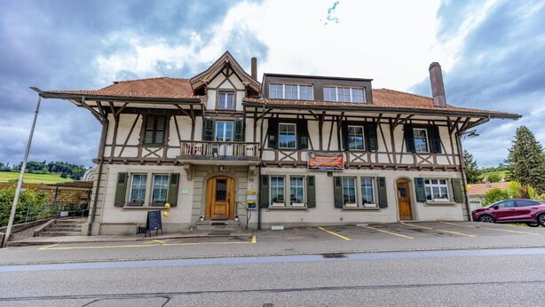 A two-story building with a traditional architectural style, featuring a balcony and a signboard. - Gasthof Sternen Thörishaus (Neuenegg)