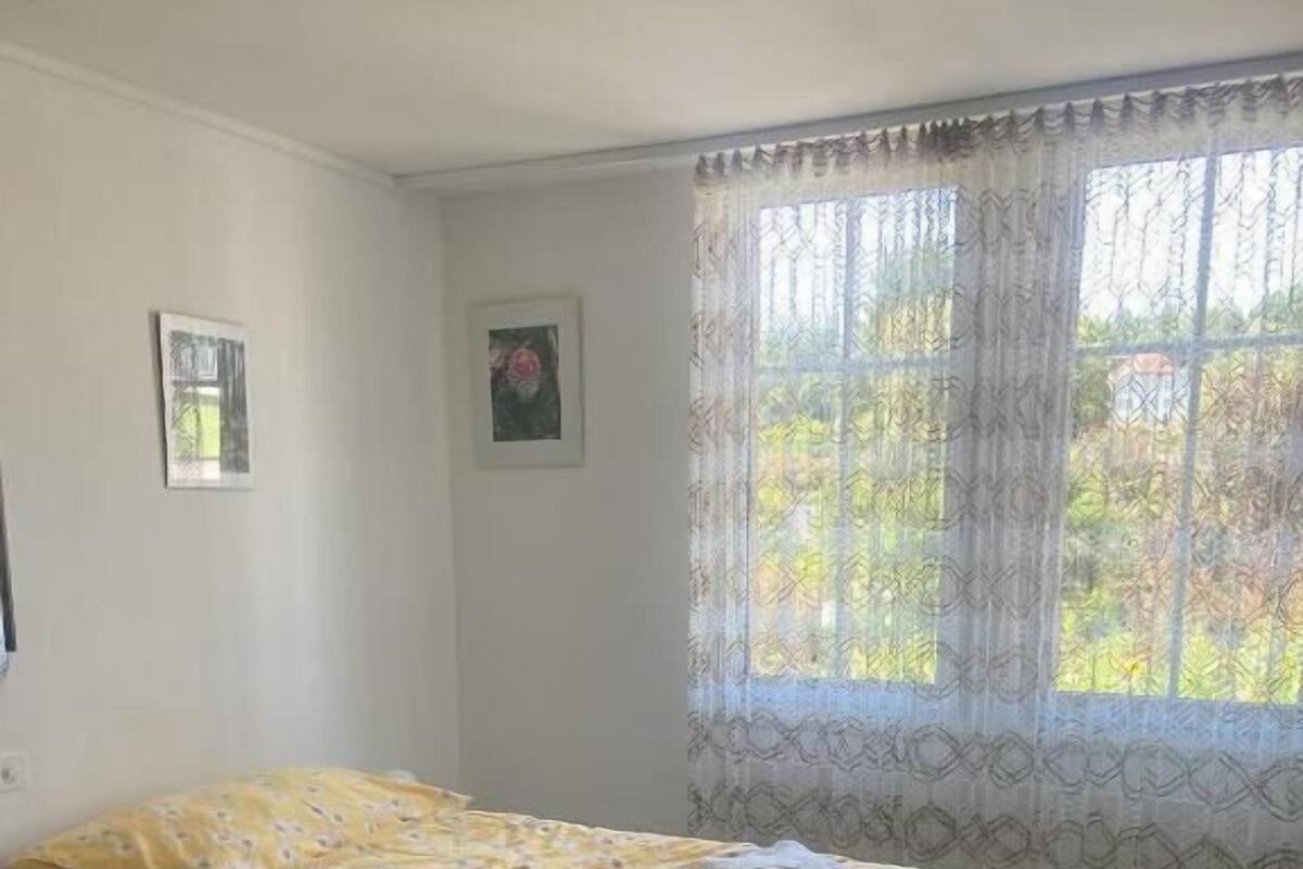 Un dormitorio con una cama, una silla y un ventanal con cortinas.
