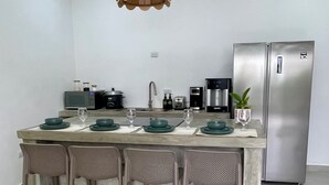 A modern kitchen with a central island, bar stools, a stainless steel refrigerator, and a hanging pendant light. - Casa Solaz-Up to 7 people, parking and private pool-Playa Negra, Puerto Viejo (Puerto Viejo de Talamanca)