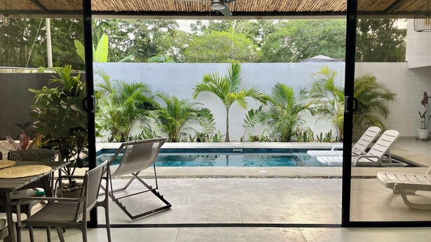 A modern outdoor pool area with a glass door leading to a lush garden. - Casa Solaz-Up to 7 people, parking and private pool-Playa Negra, Puerto Viejo (Puerto Viejo de Talamanca)