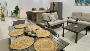 A modern living room with a dining area, featuring a sofa, coffee table, and a kitchen in the background. - Casa Solaz-Up to 7 people, parking and private pool-Playa Negra, Puerto Viejo (Puerto Viejo de Talamanca)