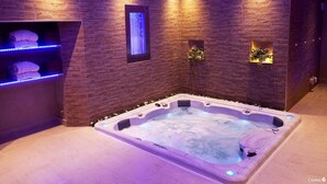 Un cuarto de spa con una tina de hidromasaje, un perchero y un estante en la pared con toallas.