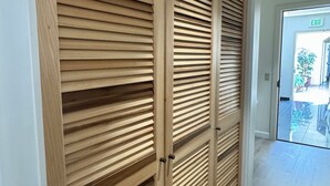 Eine Holztür mit horizontalen Lamellen, ein Ausgangsschild darüber und ein Blick ins Freie durch eine Glastür.