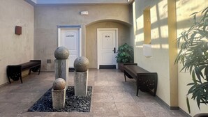 Eine Hotellobby mit Oberlicht, einer Bank, einer mit 'Laundry' beschrifteten Tür und einem Blumentopf.