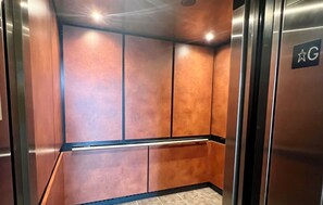 An elevator interior with metallic walls and a star-shaped sign indicating the ground floor. - La Jolla Hotel Suite with ocean view from balcony (San Diego)