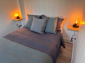 Un dormitorio con cama, almohadas y lámparas de noche.